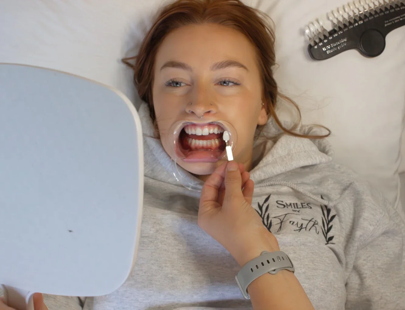 Client checking her whitened smile in a hand mirror