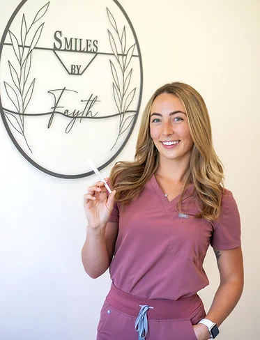 Fayth Irwin, Registered Dental Hygienist, beside the Smiles By Fayth sign