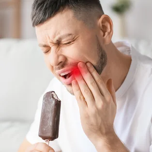Man with a frozen treat, wincing from sensitivity