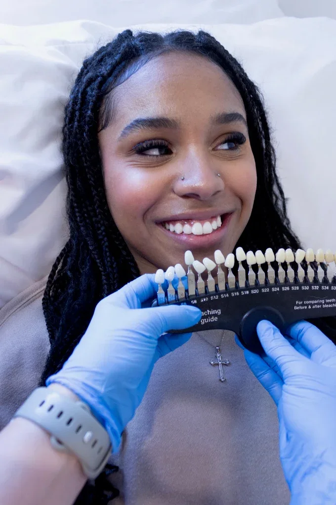 Smiling client holding a shade guide after her whitening session